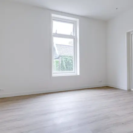 Lichte kantooruimte te huur op Graaf Florislaan 40, Hilversum. De ruimte is ongemeubileerd en heeft een groot raam, houten vloeren en dubbele deuren, ideaal voor kantoorinrichting.