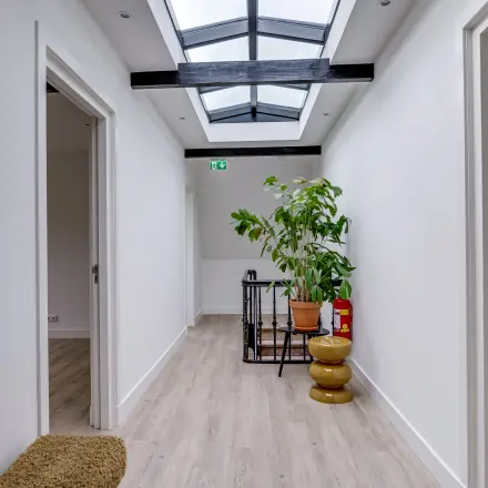 Heldere kantoorruimte in Hilversum met houten vloer, dakramen en planten. Ideaal voor wie een lichte kantoorpand wil huren aan de Graaf Florislaan 40.