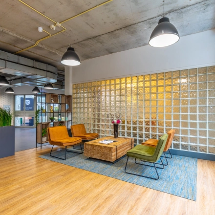Moderne kantoorruimte huren op Mozartlaan 25 in Hilversum met een stijlvolle zithoek, glazen wand, en houten vloer.