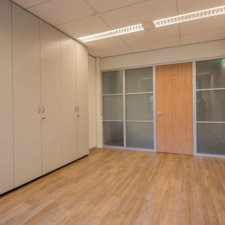 Onverharde kantoorruimte op Mozartlaan 25, Hilversum, met houten vloer en inbouwkasten, ideaal voor wie een kantoorpand wil huren. Geen meubilair aanwezig, klaar voor eigen inrichting.