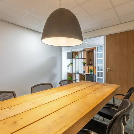 Stijlvolle kantoorruimte met houten tafel en moderne stoelen op Mozartlaan 27, Hilversum. Zoek je kantoorruimte te huur? Hier kan het. Veelzijdig en functioneel, perfect voor je zakelijke ontmoetingen.