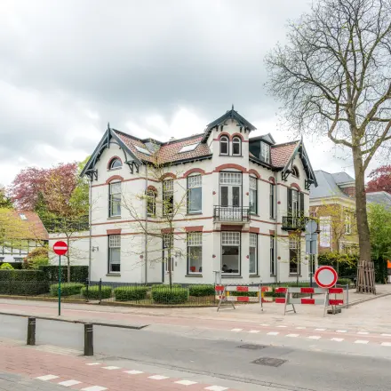 Kantoorpand aan de Oude Enghweg 8 in Hilversum, geschikt voor kantoorruimte huren. De buitenkant van een historisch gebouw met karakteristieke details en groene omgeving.