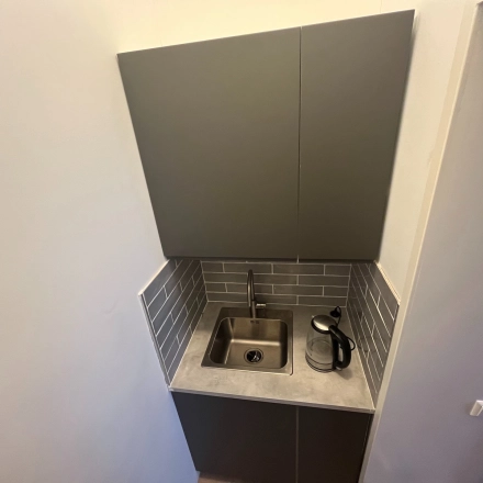 Compacte pantry met grijze kasten en een kleine gootsteen in kantoorpand op Oude Enghweg 8, ideaal voor een kantoorruimte huren in Hilversum.