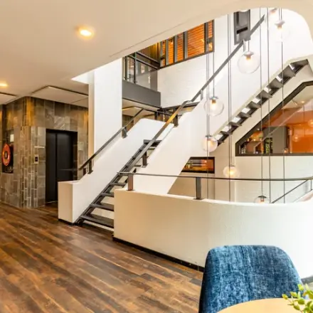 Modern kantoorpand op Steijnlaan 16, Hilversum met een stijlvolle houten vloer en open trap. Ideaal voor het huren van kantoorruimte.