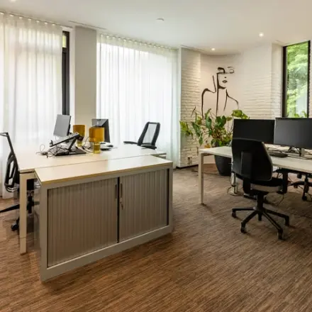 Gemeubileerd kantoor met bureaus en computers, geschikt voor kantoorruimte huren op Steijnlaan 16, Hilversum. Licht en modern design met kunst aan de muur.