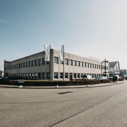 Grijs kantoorpand aan de Meidoornkade 22 in Houten met parkeerplaatsen en vlaggenstokken aan de voorzijde.