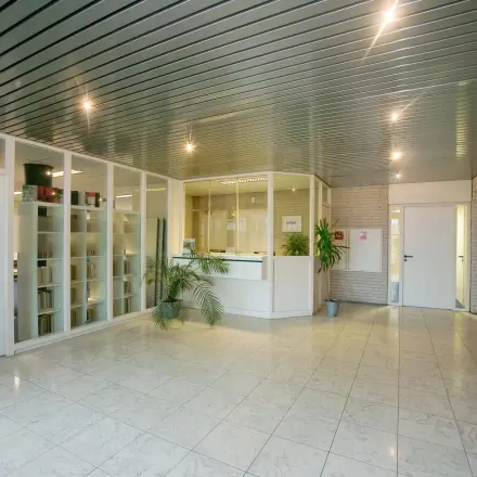 Ruime, lichte kantoorruimte huren op Sandtlaan 36 in Katwijk, met glazen wanden, tegelvloer en ingebouwd boekenrek. Ideaal kantoorpand voor zakelijke huur.