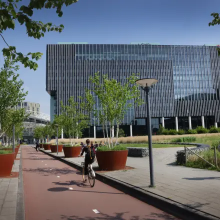Moderne buitenkant van een kantoorpand op Bargelaan 200, Leiden, met groene elementen en strakke lijnen. Mensen lopen en fietsen langs het gebouw.