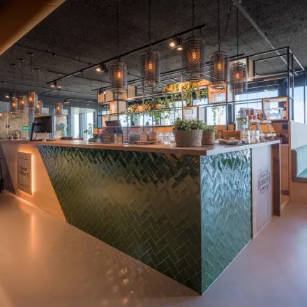 Moderne kantoorruimte huren op Bargelaan 200, Leiden met stijlvolle inrichting en groen betegelde balie, omgeven door grote ramen die veel natuurlijk licht binnenlaten.