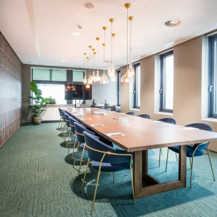 Stijlvolle kantoorruimte met grote houten tafel en blauwe stoelen, geschikt voor vergaderingen op Bargelaan 200, Leiden. Ideaal voor wie kantoorruimte wil huren met een inspirerende uitstraling.