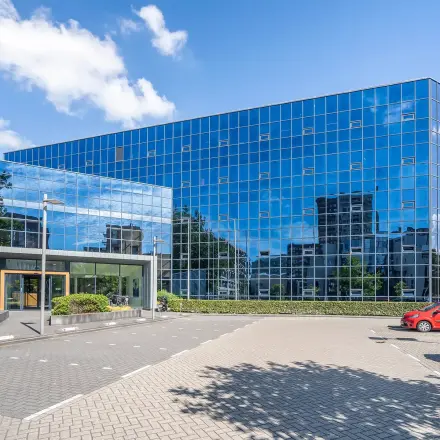 Het moderne kantoorpand aan Kanaalpark 140 in Leiden heeft een opvallende glazen gevel, met goed onderhouden parkeerplaatsen aan de voorzijde. Ideaal voor kantoorruimte huren in een eigentijds gebouw.