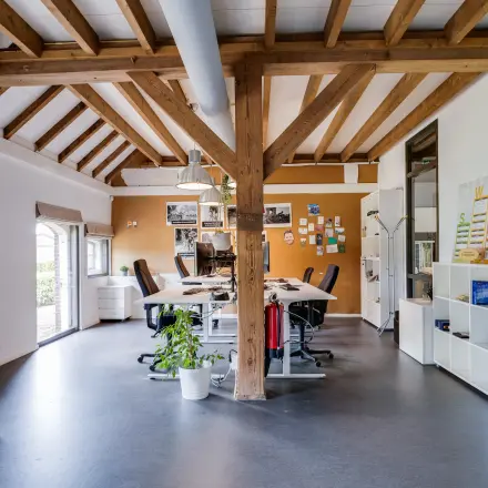 Gezellige kantoorruimte met houten balken en lichtinval op Hamersveldseweg 120, ideaal voor wie een inspirerende plek in Leusden wil huren. Voorzien van bureaus en stoelen, deze kantoren bieden volop daglicht.