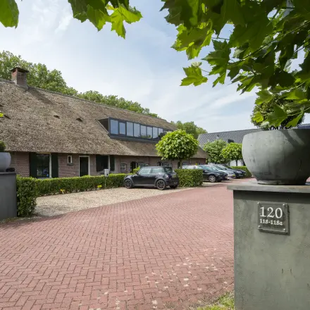 Kantoorpand aan de Hamersveldseweg 120 in Leusden, met een rieten dak en een ruime parkeerplaats voor meerdere auto's.