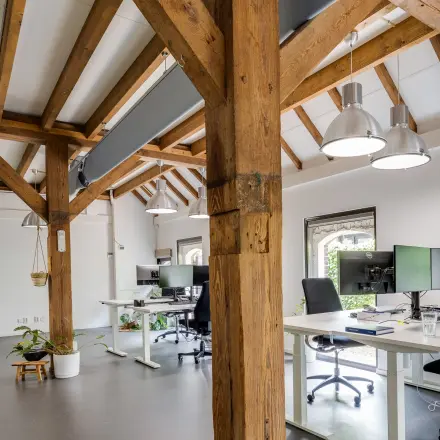 Kantoorruimte huren in Leusden met zichtbare houten balken en moderne werkplekken. Ruim en licht, met ergonomische bureaus en stoelen. Ideaal voor productiviteit.