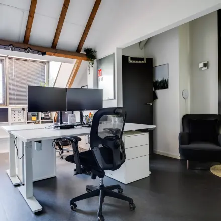 Lichte kantoorruimte te huur in Leusden met houten balken en moderne werkplekken. Groot bureau met dubbele monitor. Gezellige sfeer voor productief werk in kantoorpand Hamersveldseweg 120.