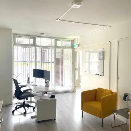 Modern kantoor met glaswand, twee bureaus en een comfortabele stoel op Wilhelminasingel 44-46 in Maastricht. Mogelijkheid tot kantoorruimte huren met een lichte, eigentijdse uitstraling.