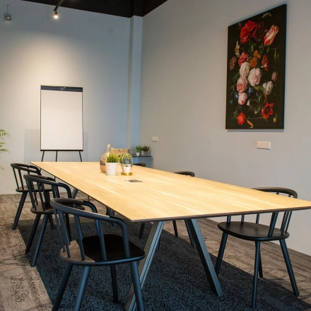 Kantoorruimte huren in Meppel op Blankenstein 400 met een lange tafel omringd door stoelen, een flipover en planten, geschikt voor vergaderingen.