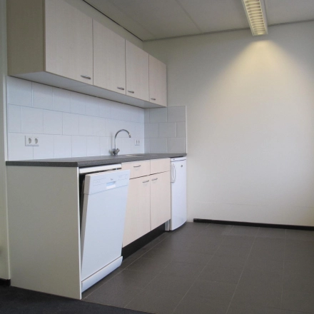 Functionele pantry in kantoorpand met witte keukenkasten, grijs aanrechtblad en ingebouwde vaatwasser. Gelegen op JC van Markenlaan 3, perfect voor bedrijven die kantoorruimte willen huren in Rijswijk.
