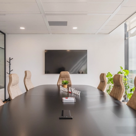 Moderne vergaderruimte in kantoorpand aan Laan van Zuid Hoorn 70, Rijswijk, met grote tafel, comfortabele stoelen, tv en veel lichtinval. Ideaal voor kantoorruimte huren.