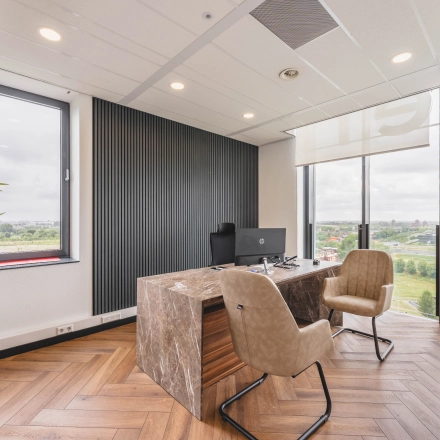 Kantoorruimte met houten vloer, marmeren bureau, comfortabele stoelen en uitzicht op Rijswijk. Geschikt voor werken en kantoorruimte huren.