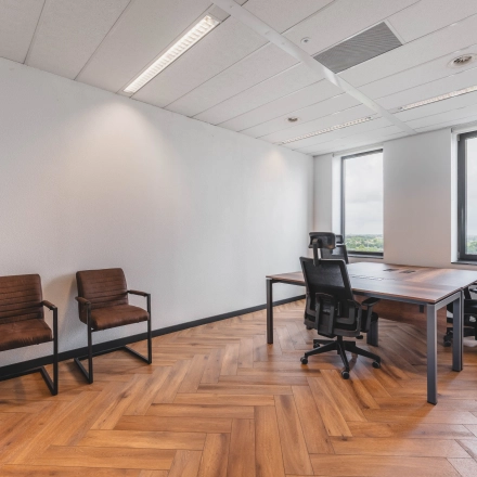 Kantoorruimte huren met houten vloer en grote ramen in Rijswijk, voorzien van vergadertafel en stoelen.