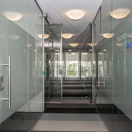 Transparante kantoorgang met glazen wanden in een kantoorpand op Boven de Wolfskuil 3, Roermond. Modern en strak ontwerp biedt mogelijkheden voor kantoorruimte huren.