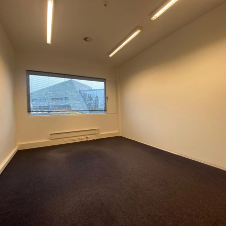 Lege kantoorruimte met grijs tapijt en grote ramen, gelegen in kantoorpand op Boven de Wolfskuil 3, Roermond. Ideaal voor wie kantoorruimte huren overweegt.