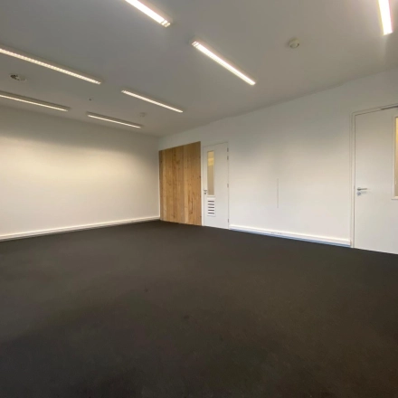 Leeg kantoorpand op Boven de Wolfskuil 3 in Roermond met witte muren en donkere vloerbedekking, perfect voor kantoorruimte huren.