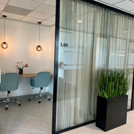 Moderne kantoorruimte huren in Rotterdam Brainpark met glazen wanden, een zitgedeelte met stoelen en een plant. Ideaal voor vergaderingen en werk in een rustige omgeving.