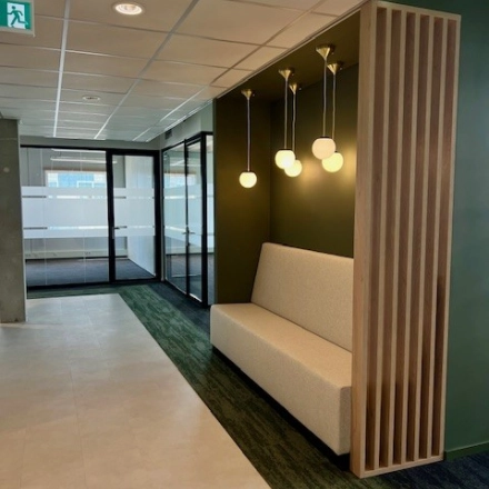 Entree van een modern kantoorpand op Bahialaan 100 in Rotterdam Brainpark, met stijlvolle verlichting en een bank tegen een groene muur. Ideale kantoorruimte huren in Rotterdam.