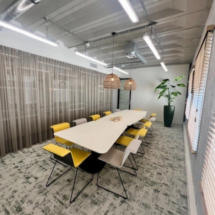 Vergaderruimte in kantoorpand op Bahialaan 100, Rotterdam Brainpark, met lange tafel en moderne verlichting. Kantoorruimte huren met comfortabele stoelen en decoratieve planten.