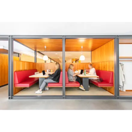 Zakelijke bespreking in moderne kantoorruimte met rode banken op Hofplein 20, Rotterdam Centraal Station. Vergadering in een professioneel ingerichte omgeving met warme houten accenten.