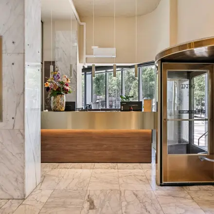 Moderne entree van een kantoorpand op Coolsingel 104, Rotterdam Centrum, met marmeren vloer en draaideur. Ideaal voor kantoorruimte huren.