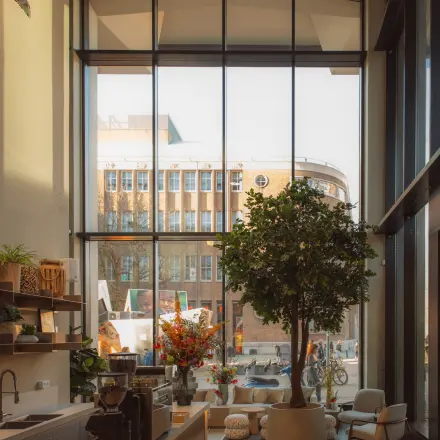 Moderne, lichte ruimte met hoge ramen aan de Coolsingel 139, ideaal voor kantoorruimte huren in Rotterdam Centrum. Groot raam met uitzicht en diverse planten en meubels aanwezig.