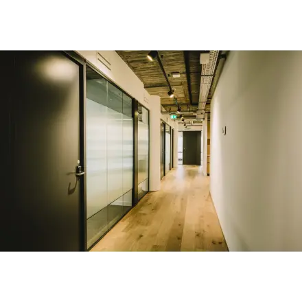 Lichte gang in kantoorpand aan de Coolsingel 65, Rotterdam Centrum, met houten vloer en glazen wanden. Ideaal voor kantoorruimte huren met moderne uitstraling.