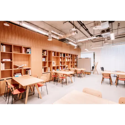 Lichte kantoorruimte in kantoorpand, Hoogstraat 185, Rotterdam Centrum, met houten tafels en stoelen, omringd door open boekenplanken. Ideaal voor wie kantoorruimte wil huren met een moderne uitstraling.