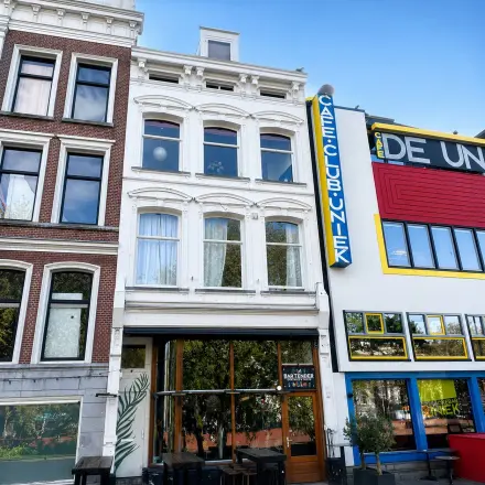 Gevel van een kantoorpand aan de Mauritsweg 33 A01 in Rotterdam Centrum, met klassieke architectuur naast moderne kleurrijke gebouwen. Ideaal voor wie kantoorruimte wil huren op een levendige locatie.