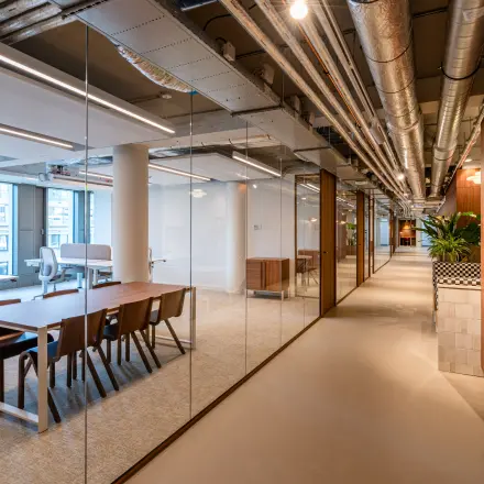 Moderne kantoorruimte in kantoorpand Stadhuisplein 9-23, Rotterdam Centrum met strak interieur en houten accenten voor huur, voorzien van glazen wanden en attente verlichting.