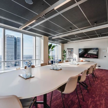 Moderne vergaderruimte met lange ovale tafel en comfortabele stoelen, grote ramen geven uitzicht op Rotterdam. Ideale kantoorruimte huren op Weena 690 voor effectieve meetings.