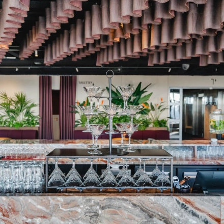 Chique kantoorpand op Weena 690 in Rotterdam Centrum met een elegant ingerichte bar en planten die de ruimte een levendige sfeer geven. Perfect voor kantoorruimte huren.