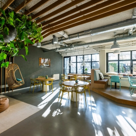 Lichte kantoorruimte met houten details en planten aan het plafond, gelegen op Westblaak 180 in Rotterdam Centrum, ideaal voor wie een kantoor wil huren. Verschillende zitopties beschikbaar.