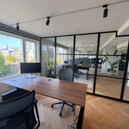 Stijlvolle kantoorruimte met houten vloer in Rotterdam Centrum, op Westplein 12, met moderne bureaus en stoelen en uitzicht op de stad. Perfect om te huren als kantoorpand.