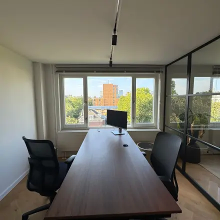 Moderne kantoorruimte met een groot bureau, twee comfortabele stoelen en een breed raam met uitzicht op de stad in het kantoorpand op Westplein 12, Rotterdam Centrum.
