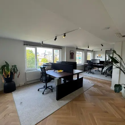 Moderne kantoorruimte te huur op Westplein 12 in Rotterdam Centrum met grote ramen, bureaus en stoelen op houten vloer.