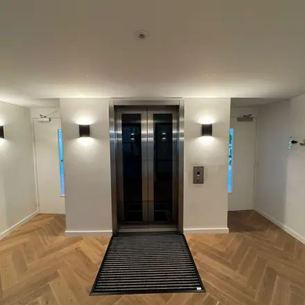 Entree van een kantoorpand met een lift aan Westplein 12, Rotterdam Centrum. De strakke houten vloer geeft een moderne uitstraling voor huur van kantoorruimte.