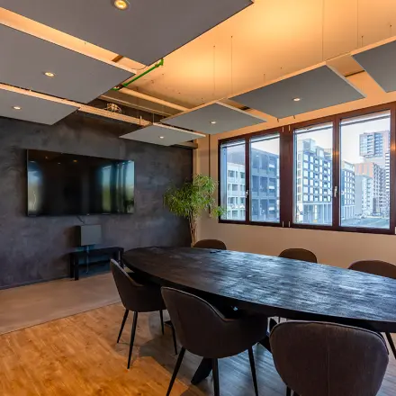 Moderne vergaderruimte in een kantoorpand aan de Kratonkade 7-27 in Rotterdam Delfshaven, met uitzicht op de skyline. Voorzien van een grote ovale tafel en stoelen.