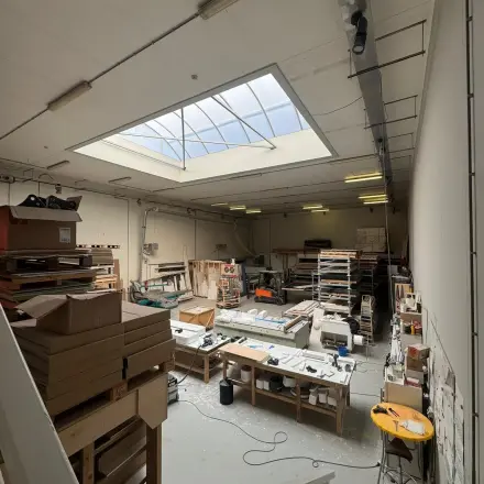 Kantoorruimte te huur in Rotterdam Delfshaven op Van Helmontstraat 17-23, met een grote glazen dakkoepel en diverse werkstations. Ideaal voor creatieve projecten en opslagmogelijkheden.