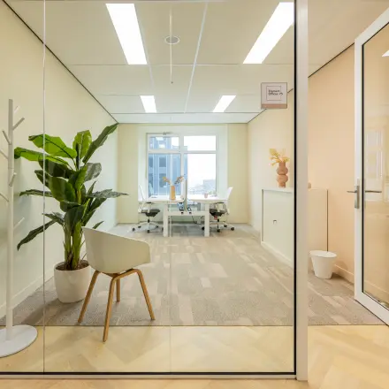 Moderne kantoorruimte te huur met glazen wanden op Wilhelminaplein 1-40 in Rotterdam Kop van Zuid. Voorzien van bureaus, stoelen en planten. Ideaal om te huren als inspirerende werkplek.