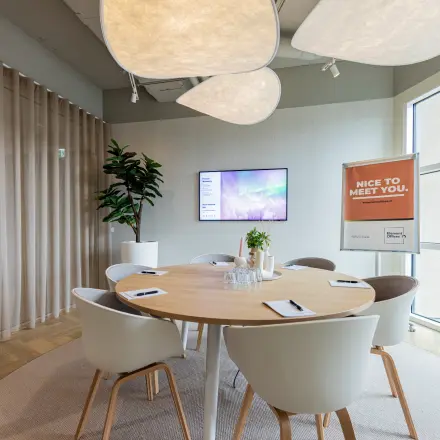 Lichte kantoorruimte huren op Wilhelminaplein 1-40, Rotterdam Kop van Zuid, met een moderne vergadertafel, comfortabele stoelen en groot scherm voor presentaties.