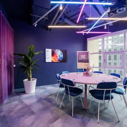 Moderne kantoorscheidingsruimte in Rotterdam Kop van Zuid, Wilhelminaplein 1-40, met kleurrijke verlichting en stijlvolle, ronde tafel voor creatief overleg. Ideale plek voor kantoorruimte huren.
